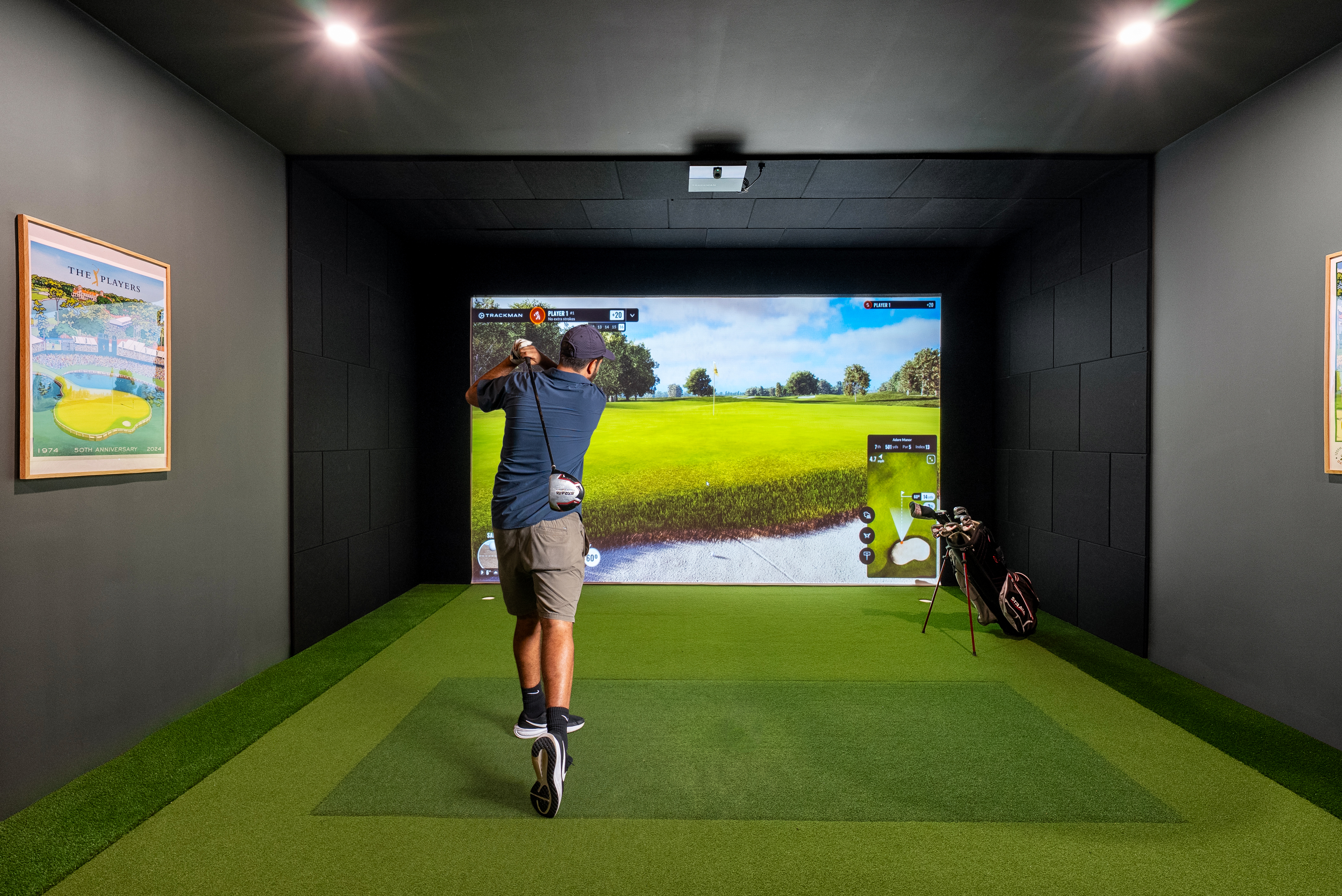 golfer swinging a club in state of the art golf simulator room golfer swinging a club in state of the art golf simulator room