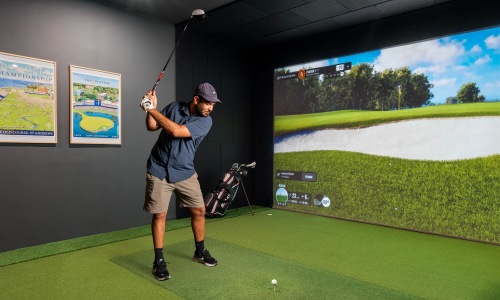 golfer swinging a club in state of the art golf simulator room