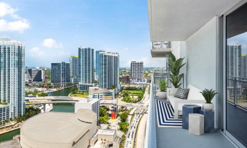 a view of a city from a patio with seating and plants
