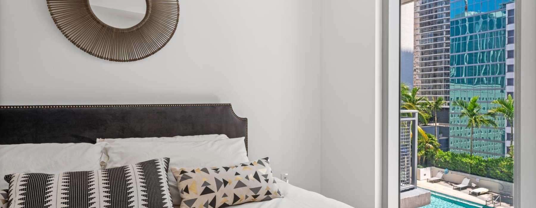 a bed in a room with a window viewing a pool