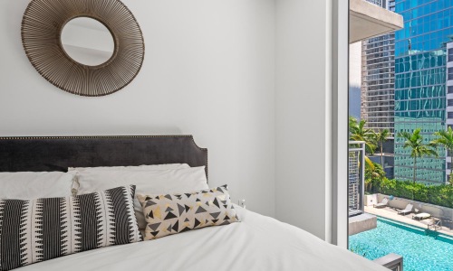 a bed in a room with a window viewing a pool